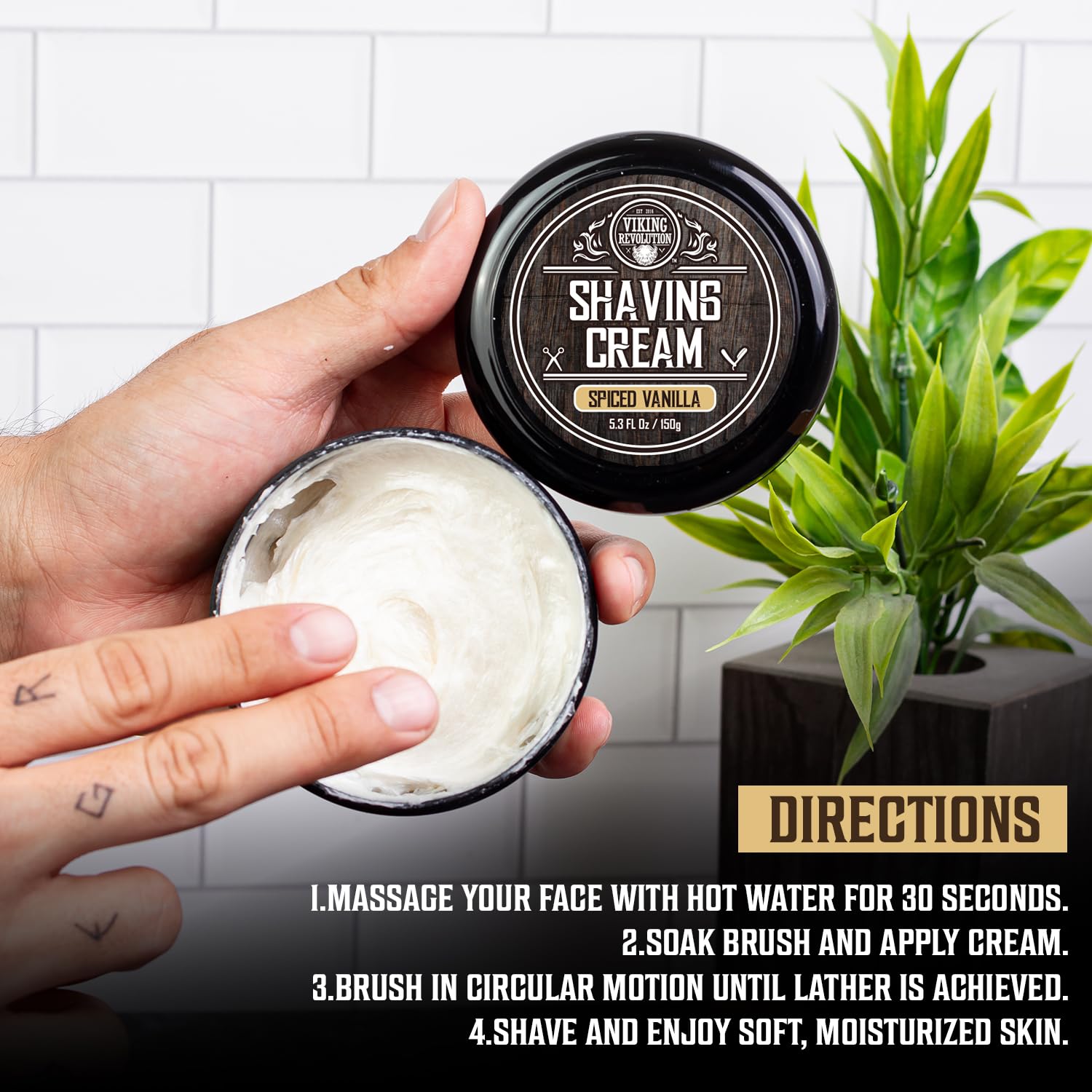 A person holds an open jar of Spiced Vanilla Shaving Cream (3.5 fl oz) above white tiles.