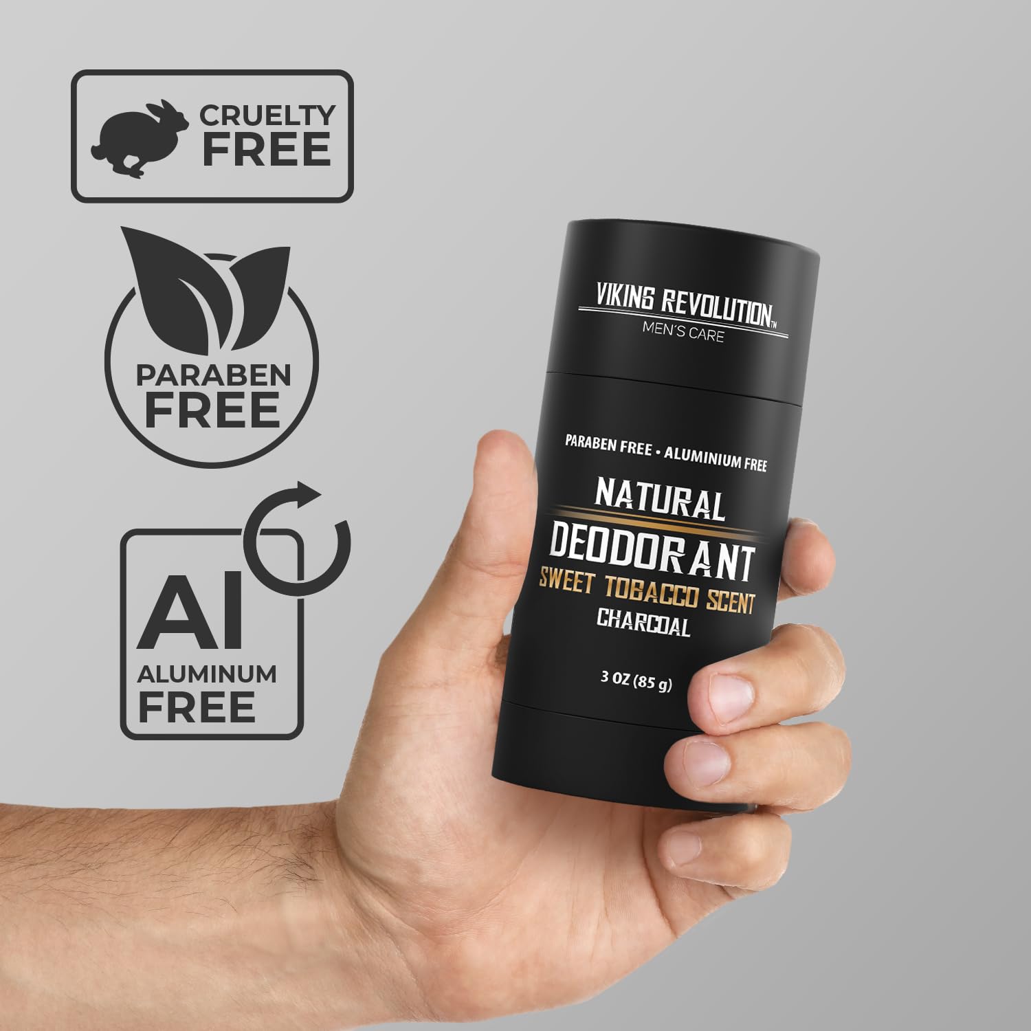 A hand holds a stick of Sweet Tobacco Natural Deodorant for men, charcoal 3oz, proudly displaying its aluminum-free, cruelty-free, and paraben-free labels.