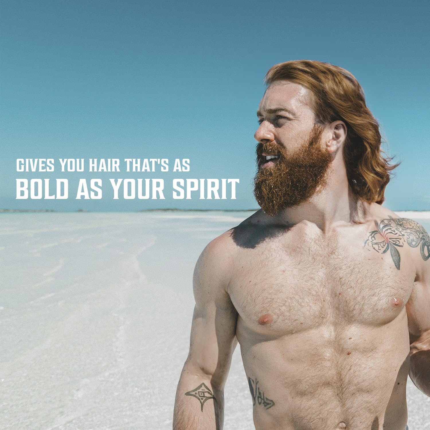 Man with beach waves and a beard stands before the ocean. (Coconut sea salt hair spray for men).