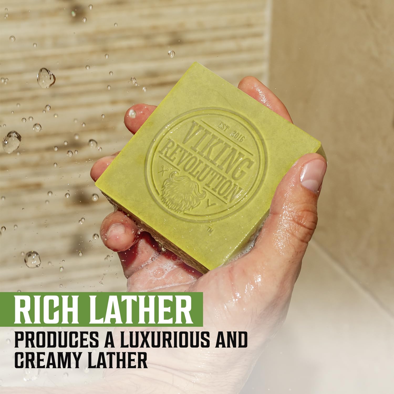 Hand holds Bergamot Natural Soap for Men under running water, creating a rich lather. Viking Revolution logo.
