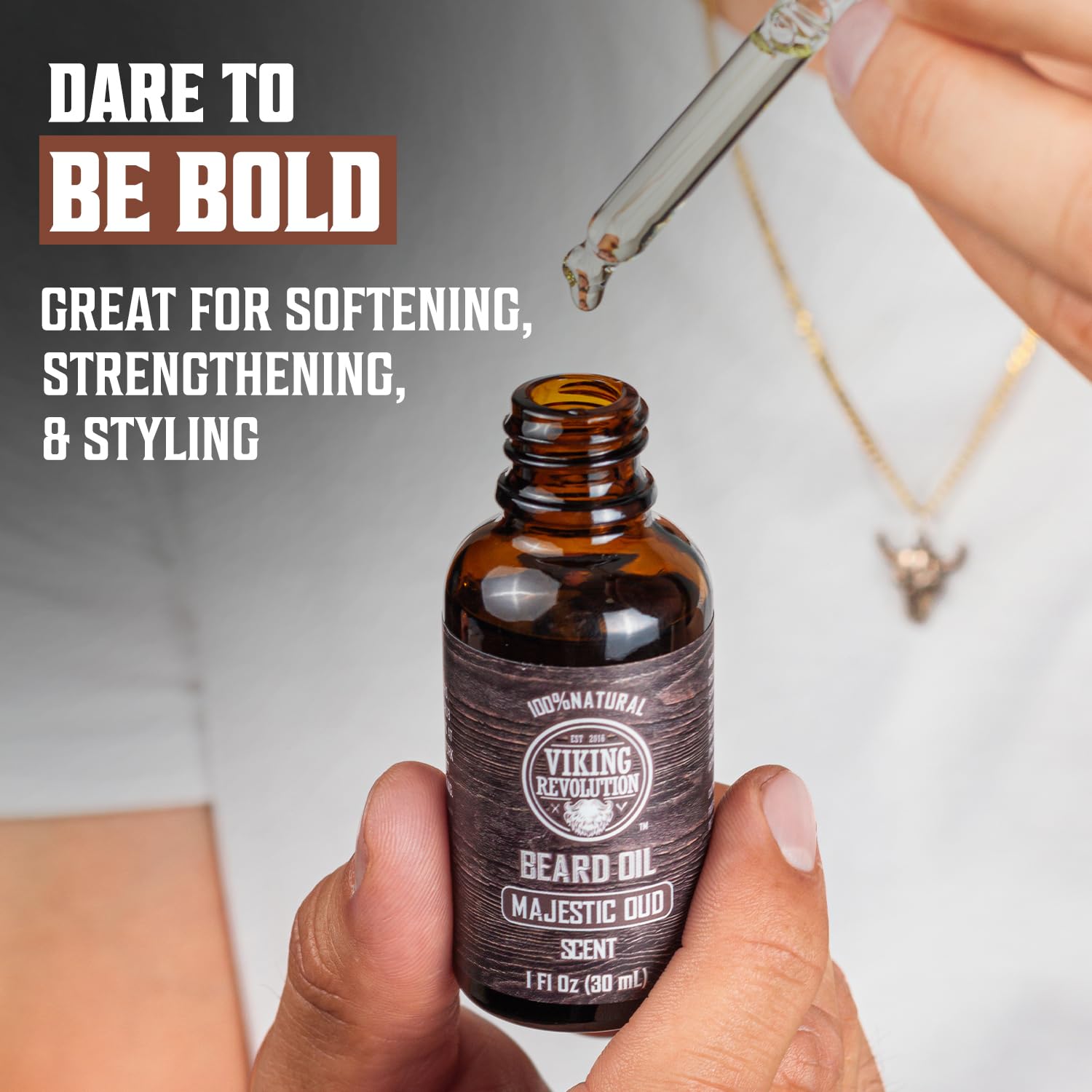 An individual applies the Majestic Oud Beard Oil by Viking Revolution using a dropper. Experience the pinnacle of natural beard care and embrace boldness.