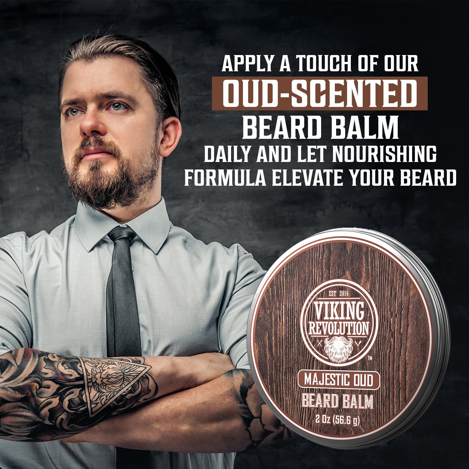 Bearded, tattooed man with folded arms promotes Majestic Oud Beard Balm. Embrace natural beard care.
