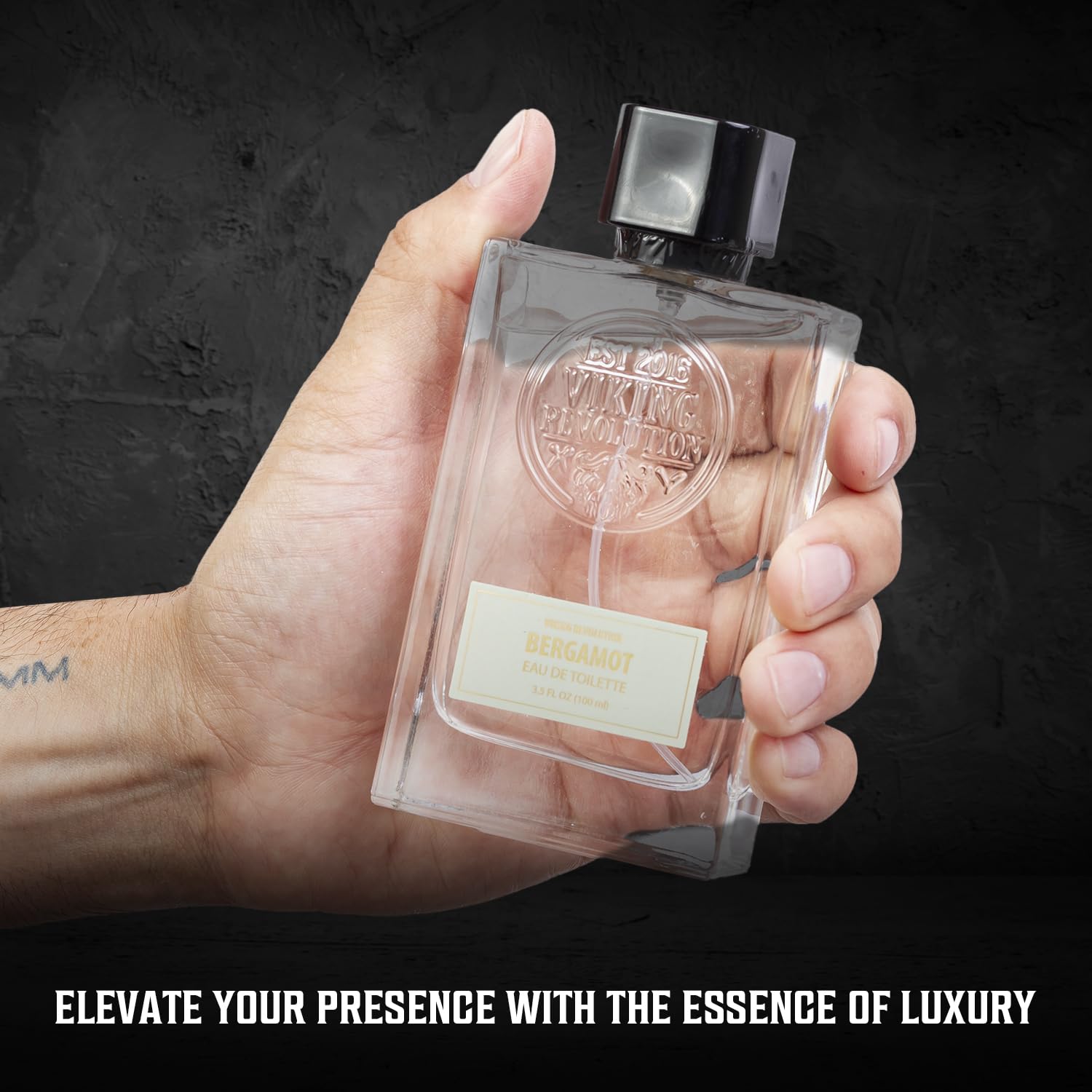 A hand holds a clear square bottle labeled "Cologne for Men 3.5 fl oz" by Viking Revolution, set against a dark background.