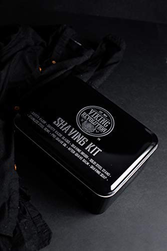 A sleek black tin labeled "Luxury Safety Razor Shaving Kit" rests on a dark cloth surface, its lid adorned with product details. Inside, essentials for beard grooming await, featuring a safety razor designed to enhance your shaving experience.