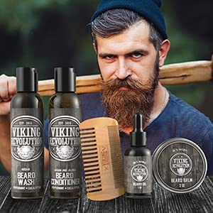 A bearded man with an axe, surrounded by a Viking-themed Beard Grooming Kit, which includes products infused with a rich sandalwood scent and accompanied by a wooden comb.
