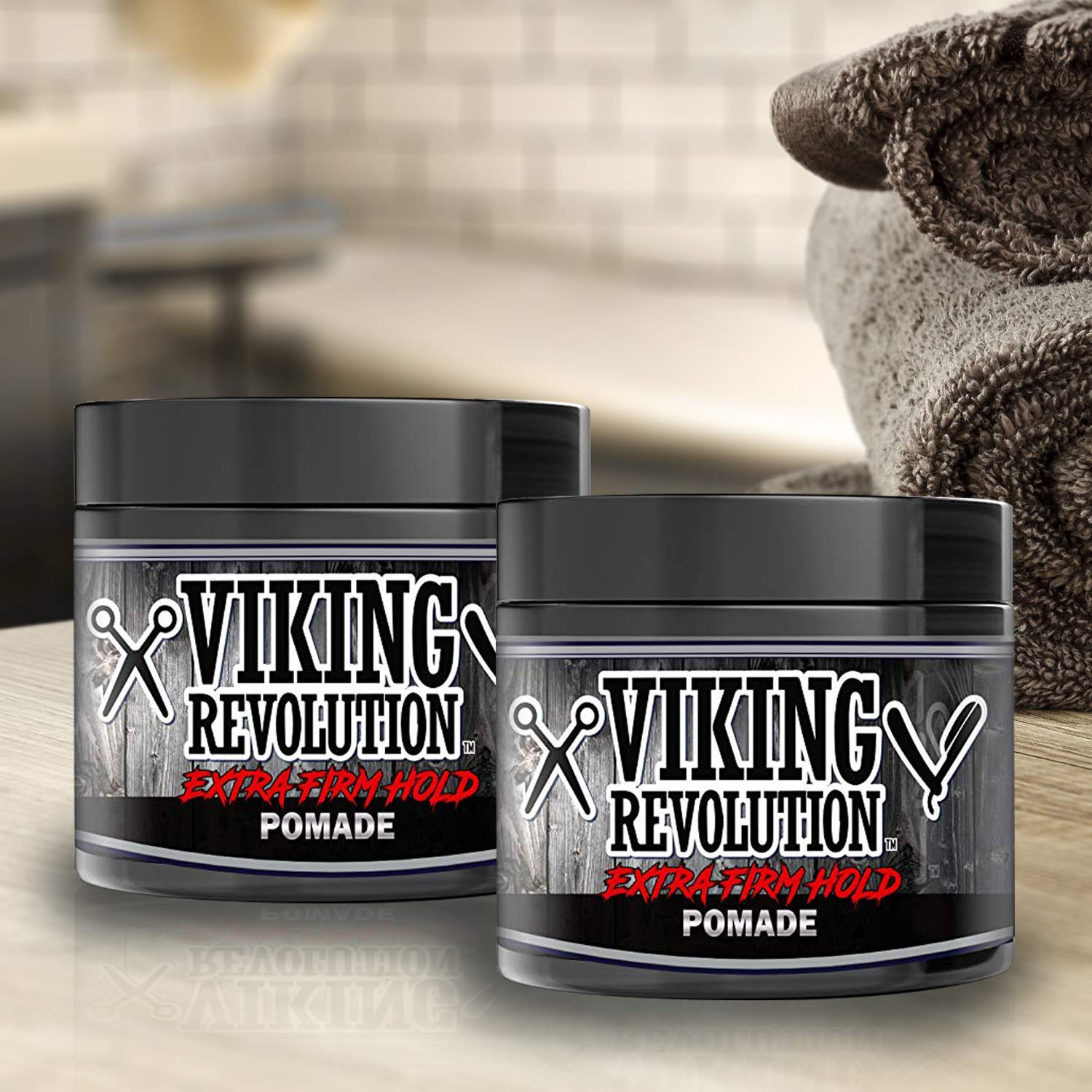 Two jars from the Pomade - 2 Pack, crafted with natural ingredients, are arranged near folded towels for a refined hair grooming experience.