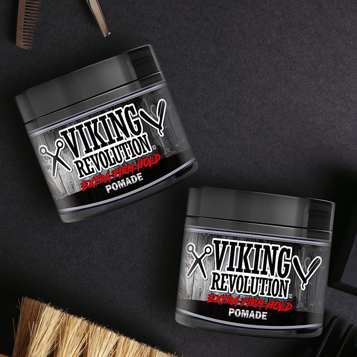 Two jars of Pomade - 2 Pack by Viking Revolution, crafted with natural ingredients, rest on a dark surface surrounded by essential hair grooming tools.