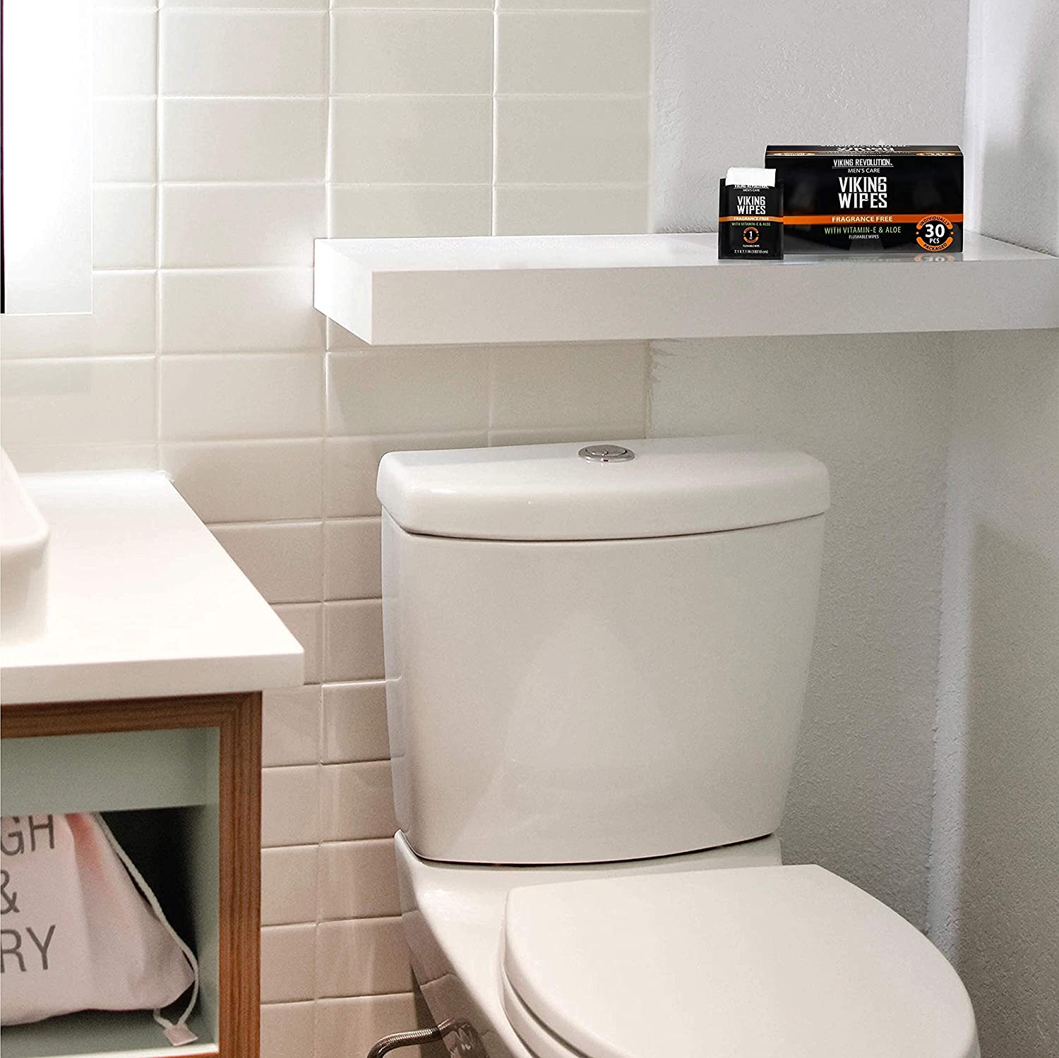 A white bathroom with a toilet and a shelf holding unscented Viking flushable wet wipes for adults.