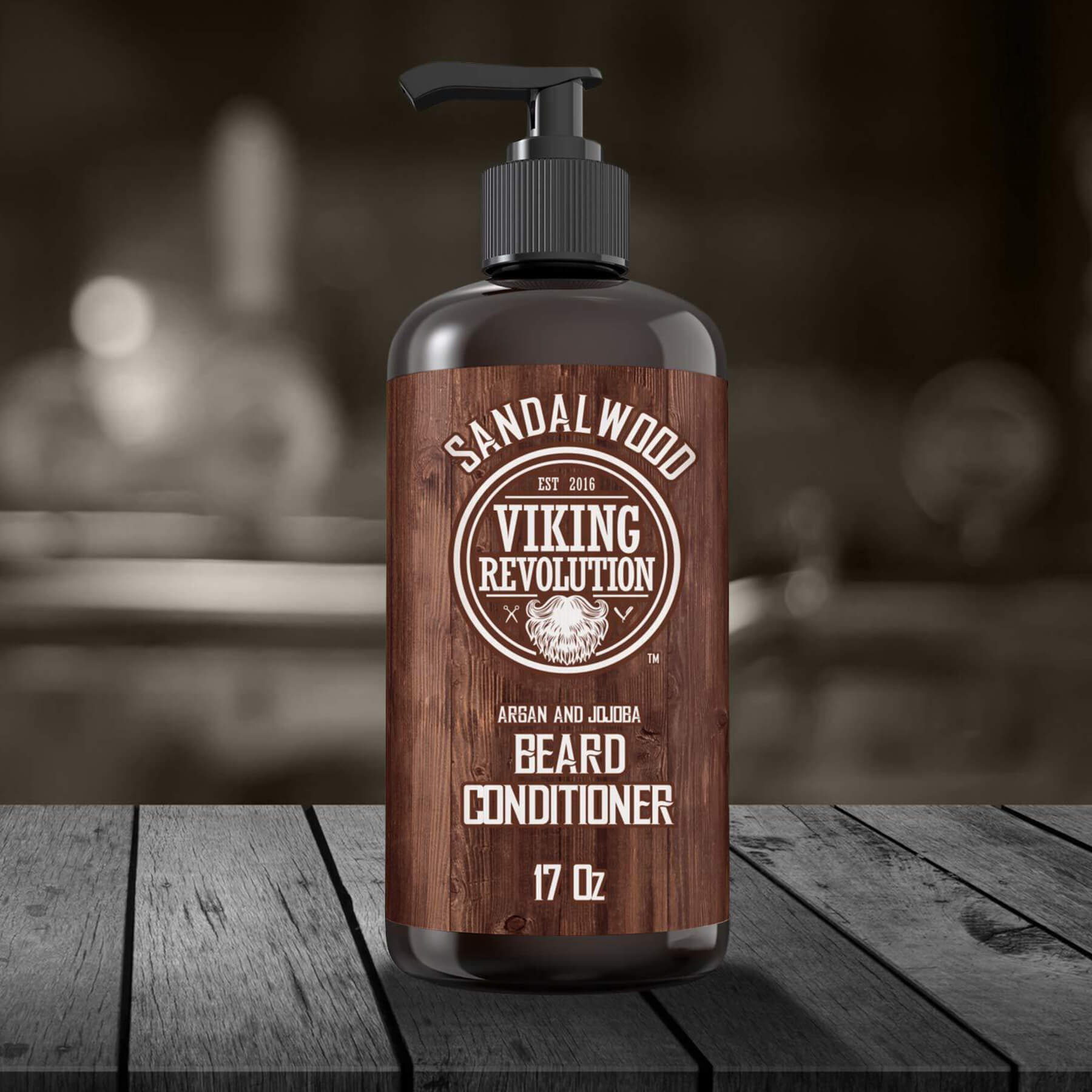 Sandalwood Beard Conditioner 17oz on a wooden surface, featuring plant-based oils and blurred background.