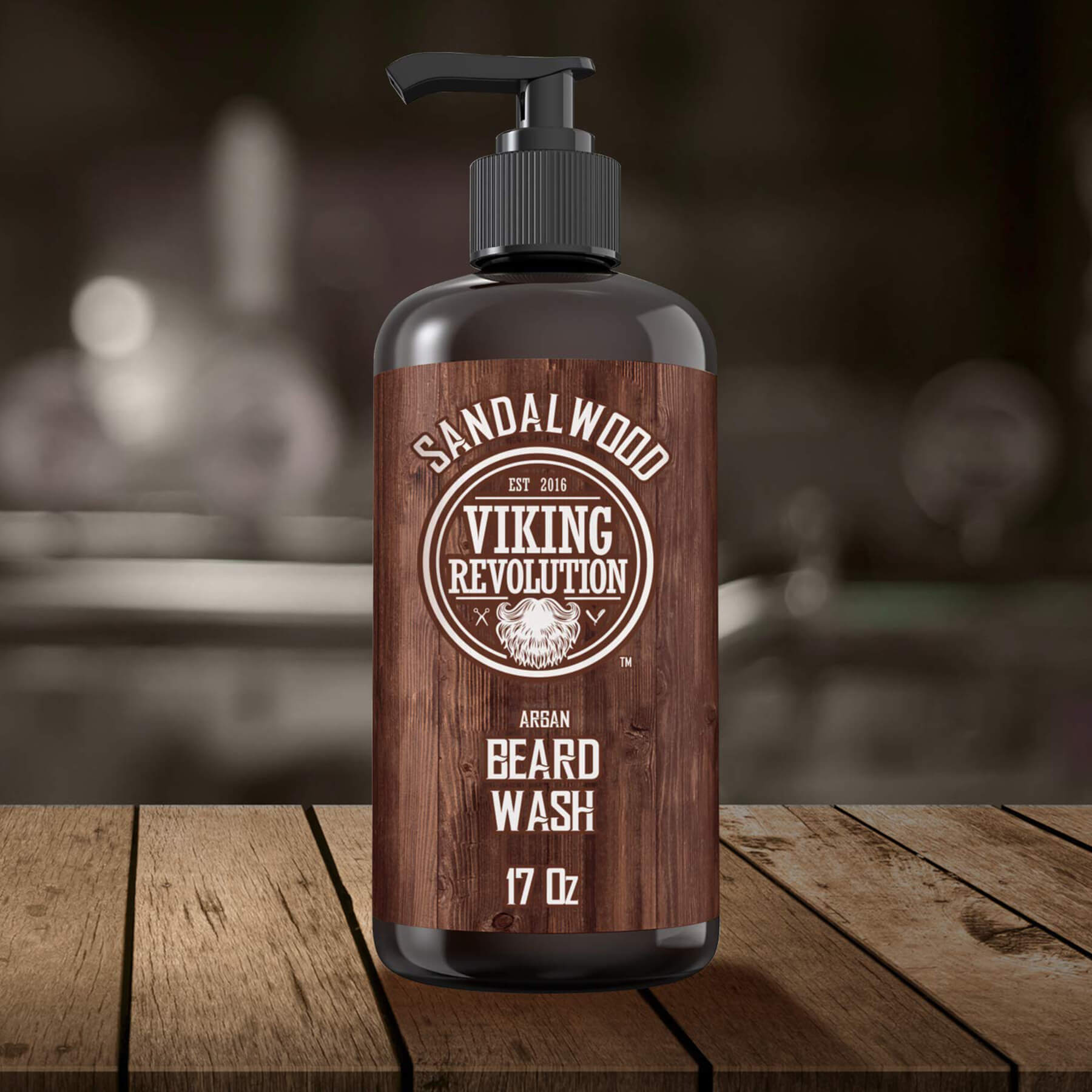 A 17oz bottle of Sandalwood Beard Wash from Viking Revolution is placed on a wooden table, providing a sandalwood fragrance that enhances your beard care routine. Experience exceptional grooming with the added assurance of a satisfaction guarantee for peace of mind during every use.