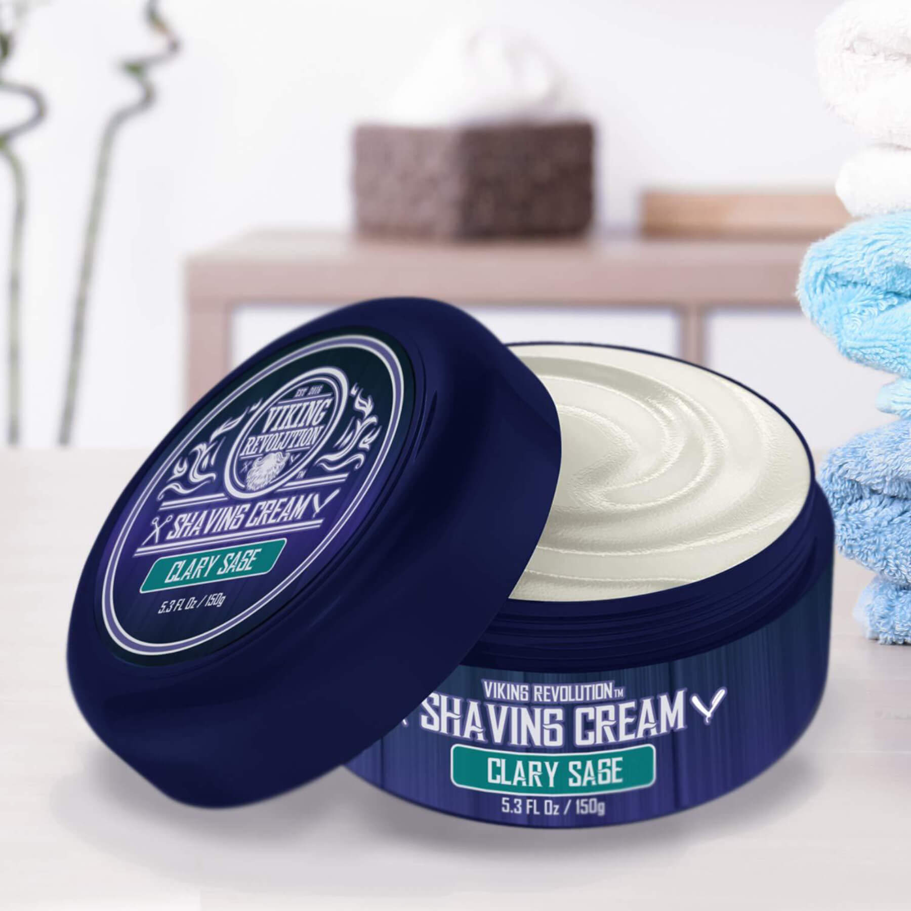 Clary Sage Shaving Cream with rich lather in a blue container against a blurred bathroom backdrop.