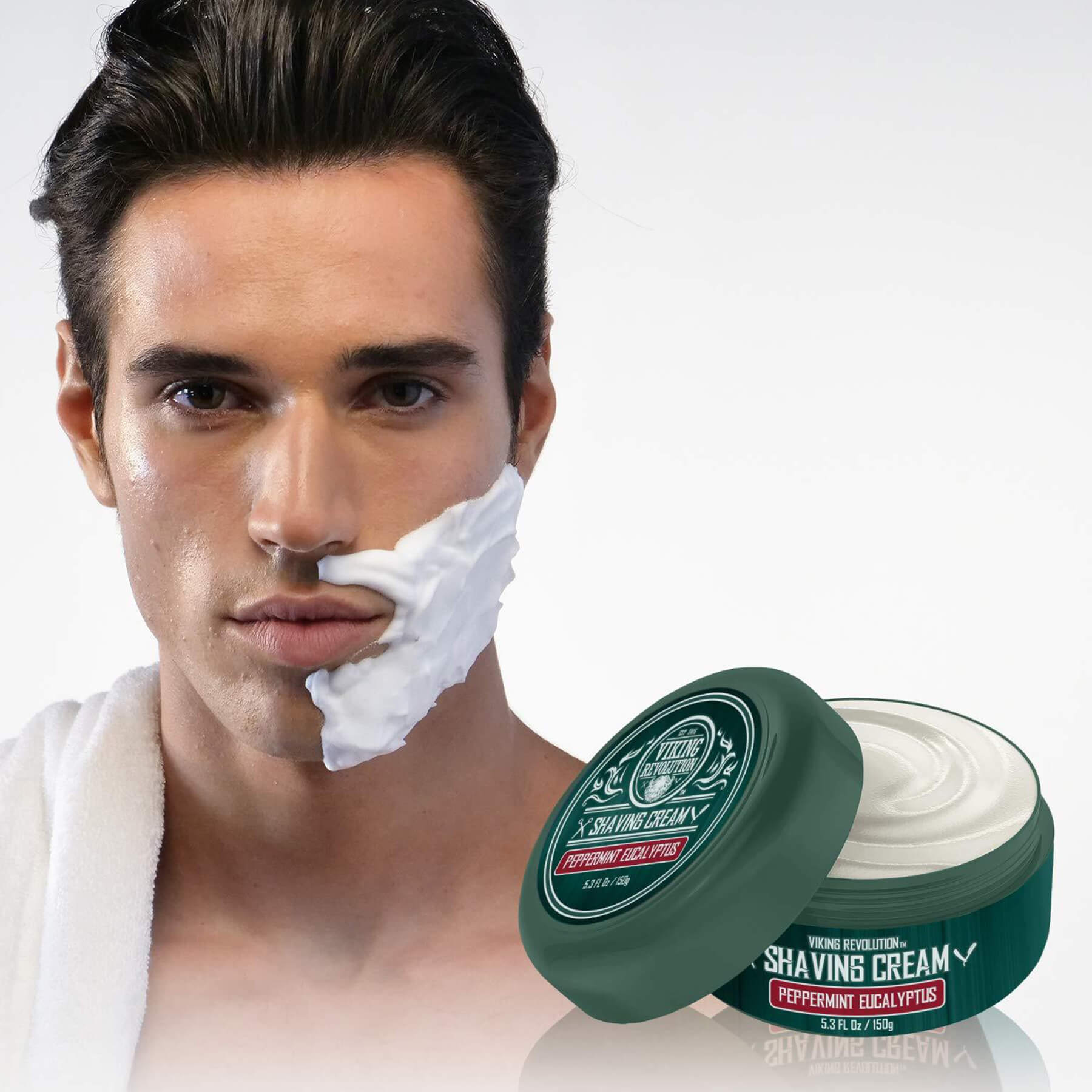 A man with shaving cream on his face is pictured, while a jar of Peppermint & Eucalyptus Shaving Cream from Revolution sits prominently in the foreground, offering an invigorating shaving experience with refreshing hints of peppermint eucalyptus.