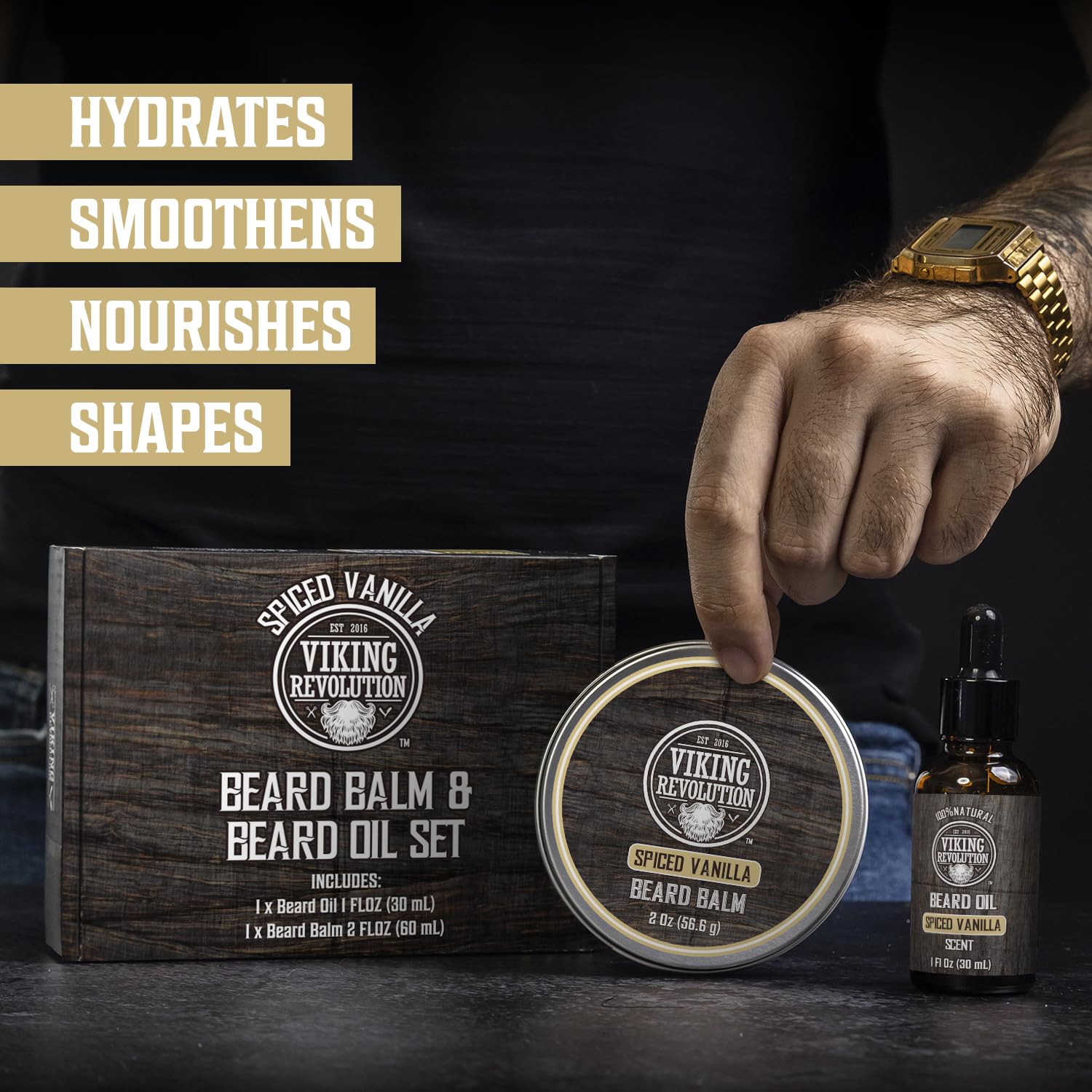 A hand holds Spiced Vanilla Beard Balm & Beard Oil Kit by Viking Revolution on a black surface.