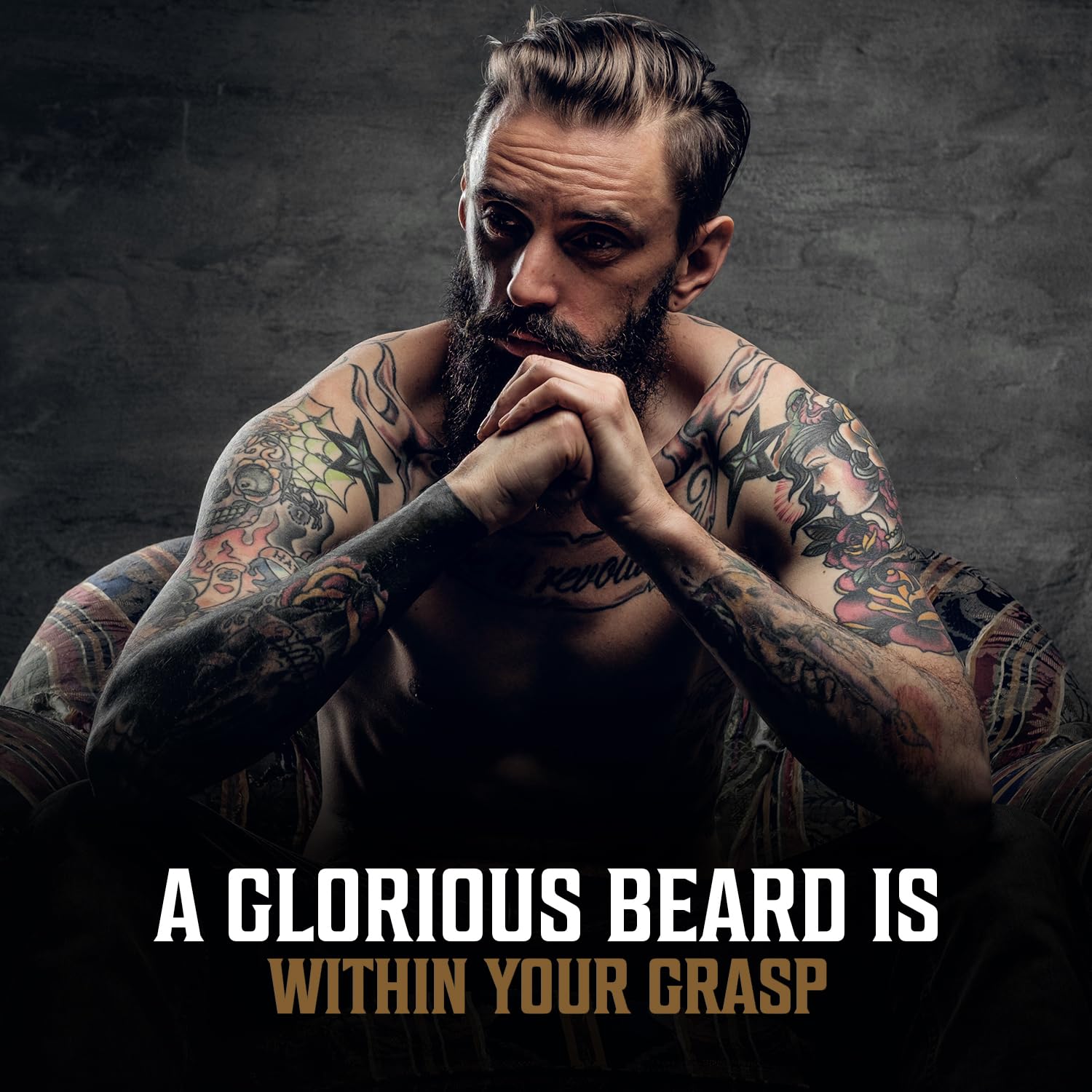 Tattooed man with a full beard sits pensively; try our 3 pack beard oil mix for a glorious beard.