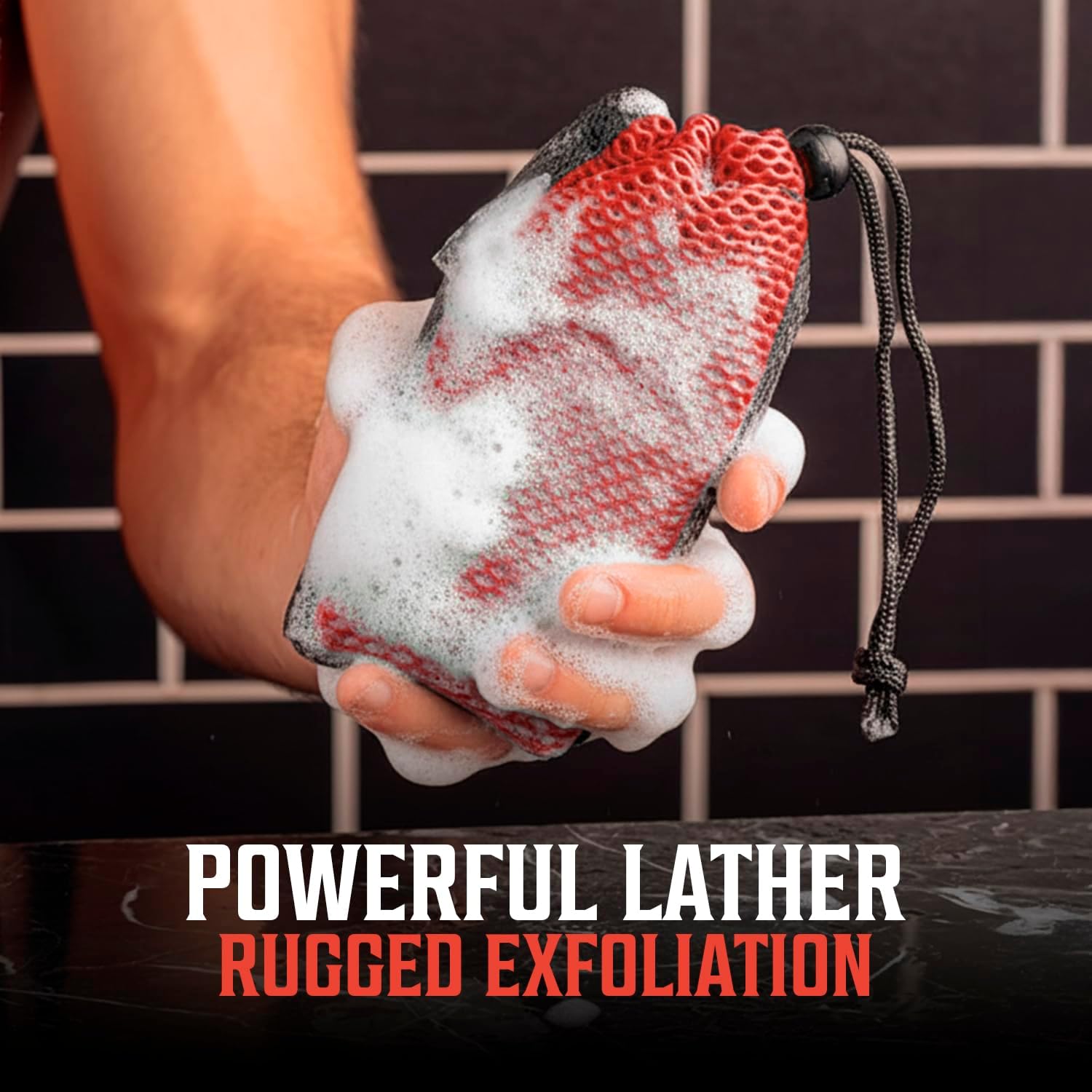 A hand holds a red Soap Bag with soap suds in front of a tiled wall.