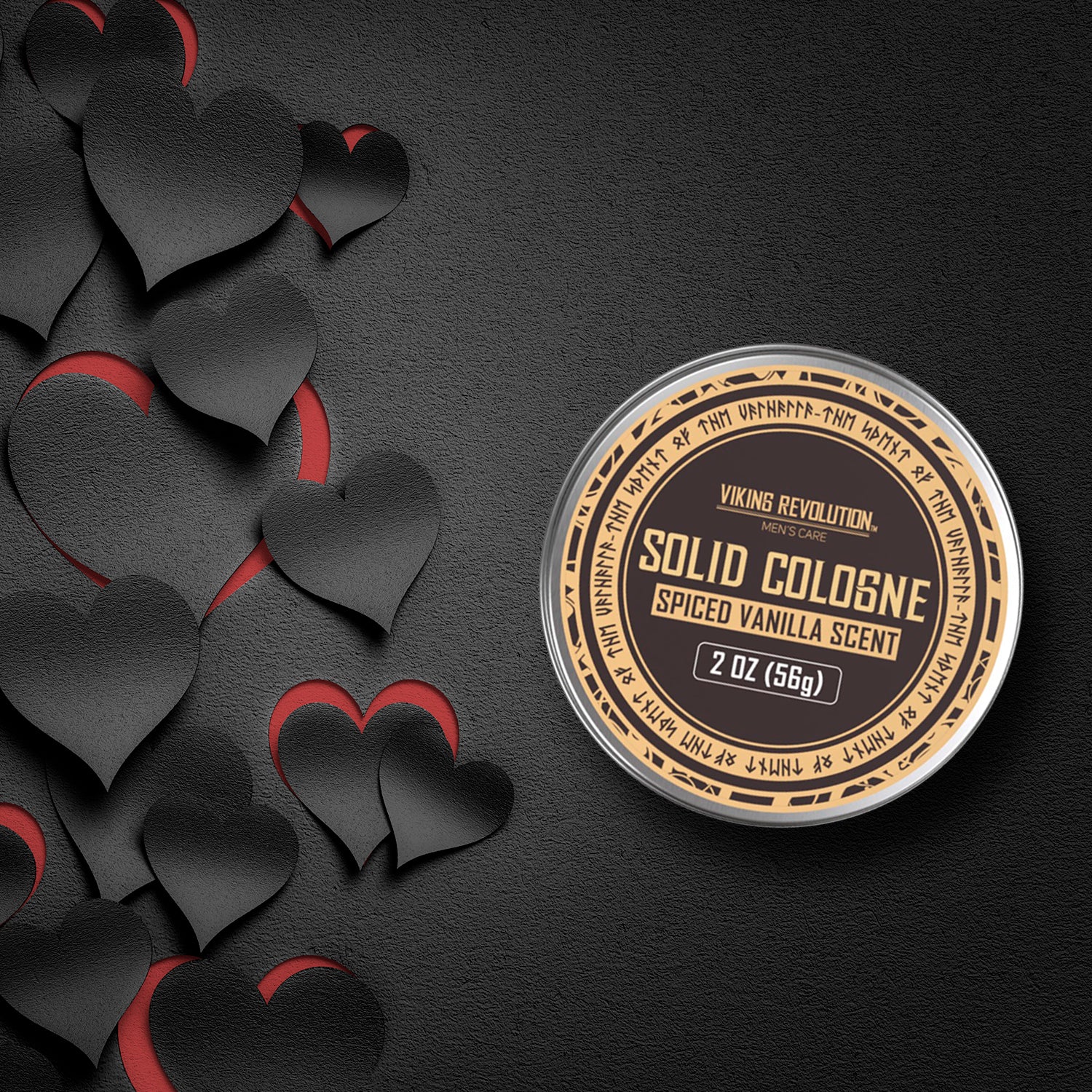 The Spiced Vanilla Men's Solid Cologne, a 2 oz tin, is elegantly displayed on a textured surface, accented with black and red heart cutouts. It's the ideal gift for men who value style and subtle sophistication.