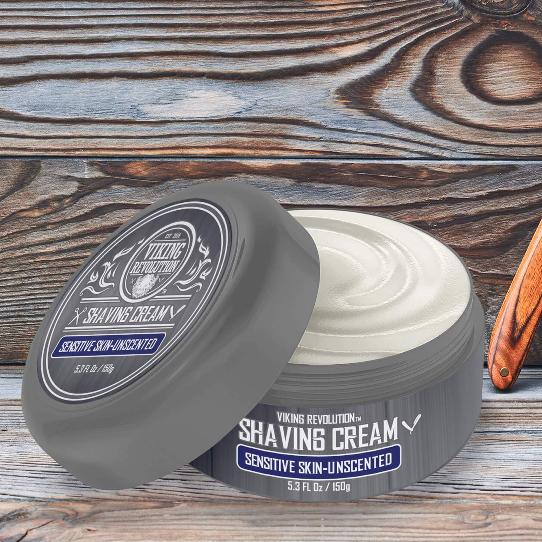 Gray tub of Shaving Cream on wood, next to a straight razor for a smooth shave experience.