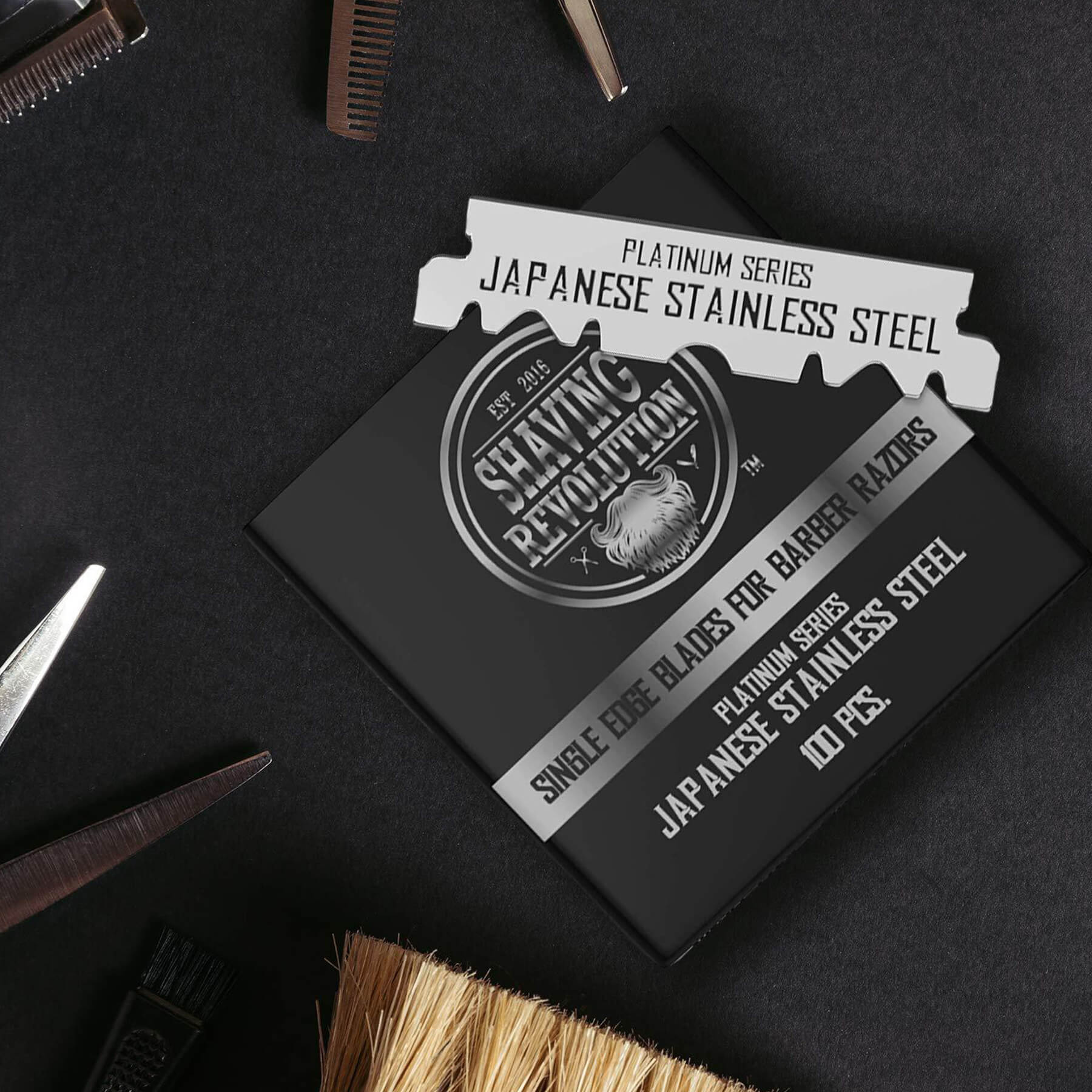 Barber tools with a black box of Barber Single Edge Razor Blades (100 count) on a dark surface.